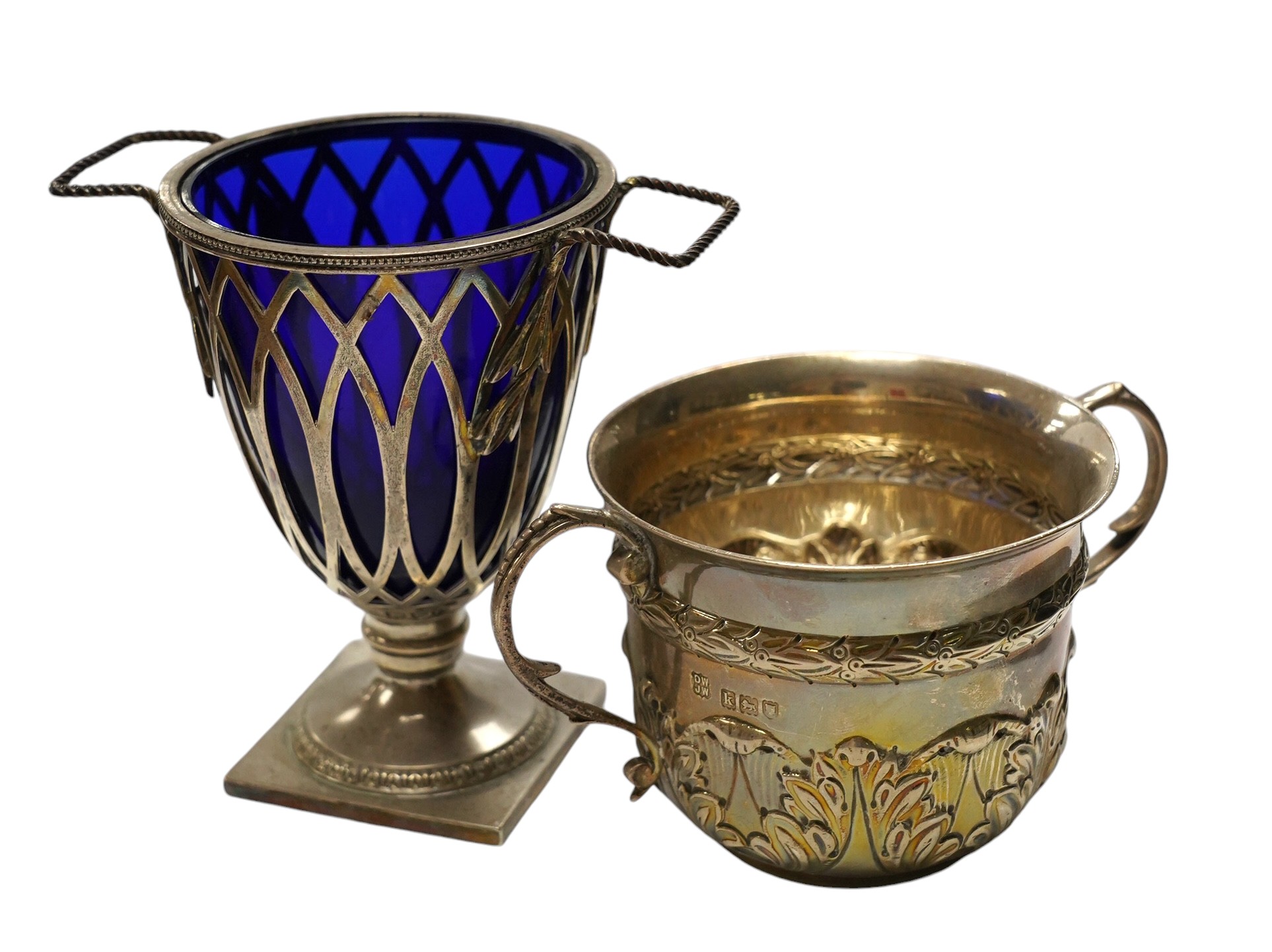 An Edwardian repousse silver porringer, Daniel & John Welby, London, 1905, height 73mm, together with a late Victorian silver two handled sugar vase with blue glass liner, London, 1895. Condition - fair